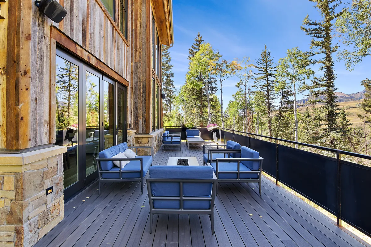 A cozy outdoor seating area featuring a fire pit, nestled among trees with mountain views in the distance. The scene is perfect for gathering, relaxing, and enjoying nature after a day of adventure.