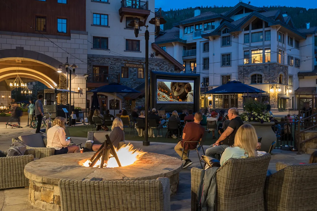 An inviting outdoor entertainment area complete with a fire pit, comfortable seating, and an outdoor movie screen, creating an ideal spot for storytelling or watching movies under the stars.